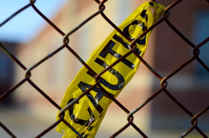 Yellow caution tape tied to a rusty chain-link fence. Our premises liability attorney in Kansas City can provide legal assistance if you or a loved one has been injured due to a property owner’s negligence.