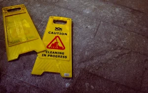 Broken wet floor caution sign laying flat on a concrete floor. Our slip and fall lawyer in Kansas City can assist you with your premises liability claim if you have been injured as a result of using a faulty staircase, slipping on a wet floor, or another hazard encountered while visiting a business or private property
