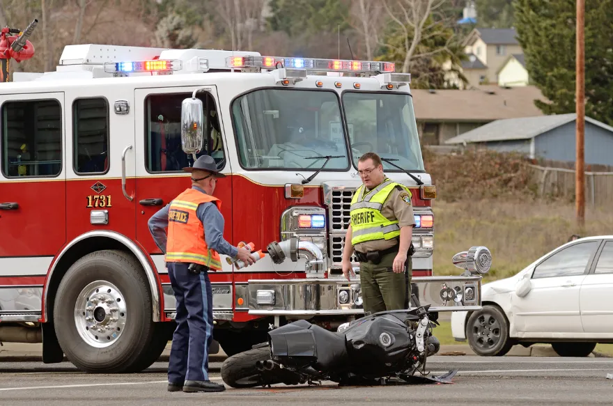 Motorcyle laying in the middle of the road next to a fire truck. Our Kansas City motorcycle accident attorneys fight for those seriously injured while riding a motorcycle.
