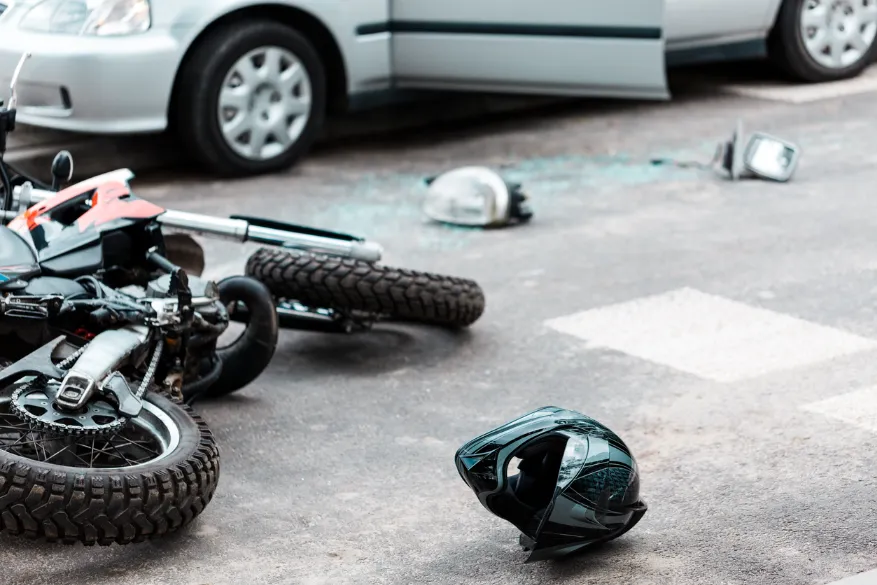 Motorcyle, helmet, and glass on the ground after a collision with a car. If you’ve been involved in an accident while riding a motorcycle, our Kansas City motorcycle accident lawyers can help you get the compensation you deserve. 