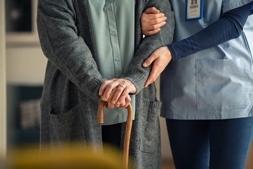 Nurse assisting senior walk with cane. Our Kansas City nursing home abuse lawyers hold assisted living homes accountable for acts of abuse and negligence. 