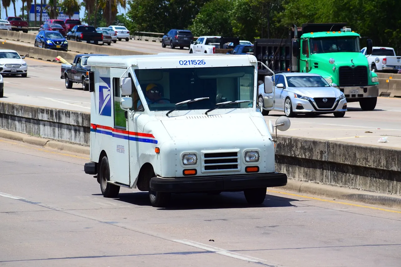 A USPS Truck driving down the highway.