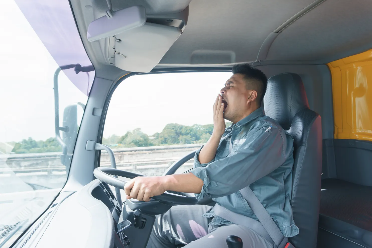 A truck driver yawning while driving. 