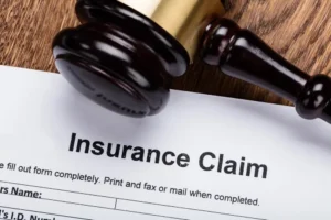 A gavel and an insurance claim form set on a table.
