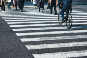 People walking and riding bicycles across a crosswalk.