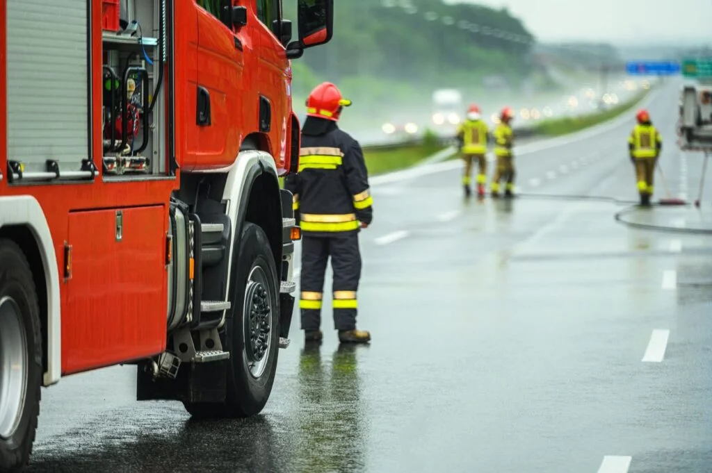 A truck and some firefighters in the middle of the highway.