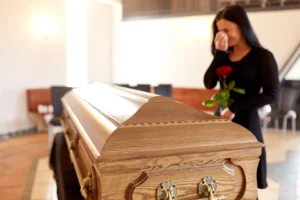 A woman crying by a casket.