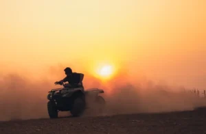 A ATV being driven toward a sunset.