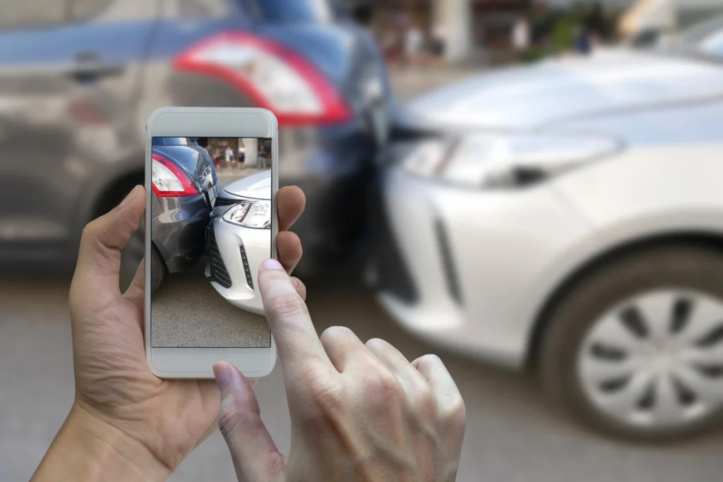 Close-up of someone taking a photo of a rear-end car accident in Kansas City, showing visible bumper damage between two vehicles.