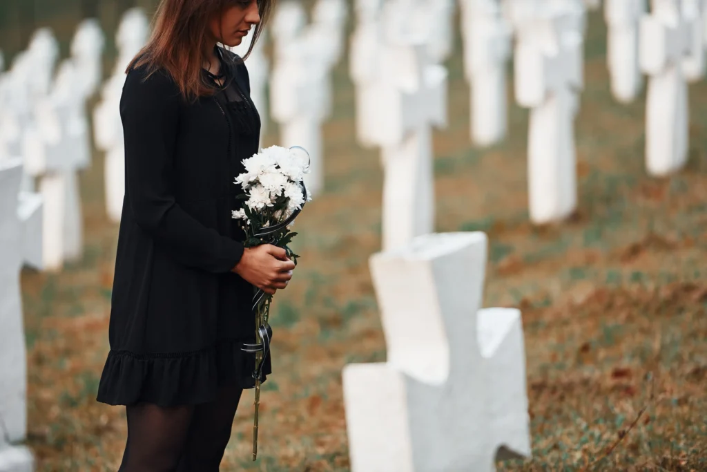 A woman holding flowers in a cementary.