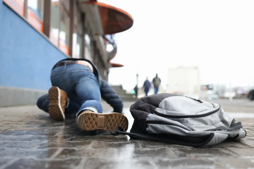 Person who slipped and fell on a wet sidewalk in St. Louis, with a backpack nearby—illustrating a potential premises liability case.