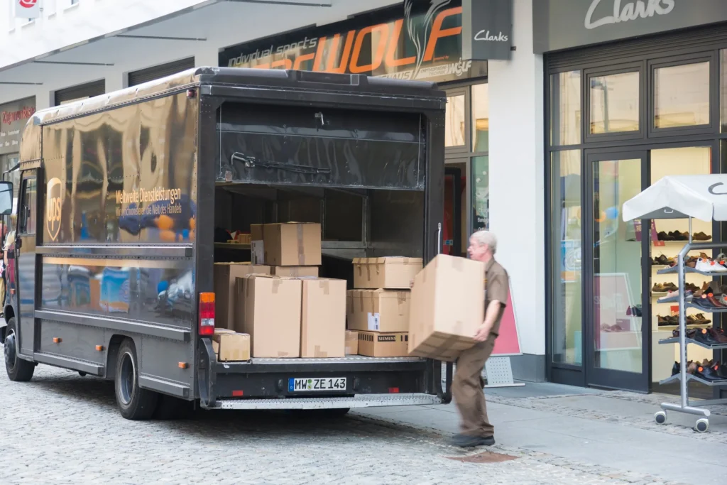 Delivery driver unloading boxes from a UPS truck in front of a storefront, representing the potential for delivery truck accidents in Kansas City.